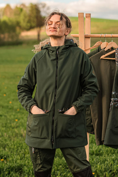 Gėlėta sodo striukė žalia — moteris lauke pievoje, matomas pilnas ilgis ir kišenės